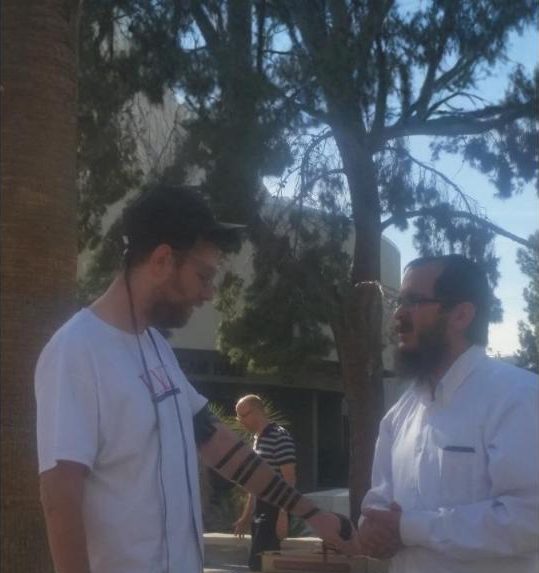 Putting on tefillin with a student on campus